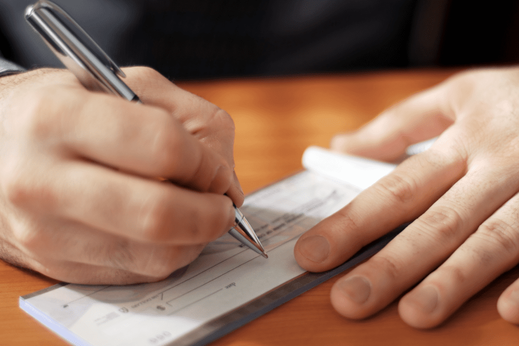 A person is filling out a paper check with a pen.