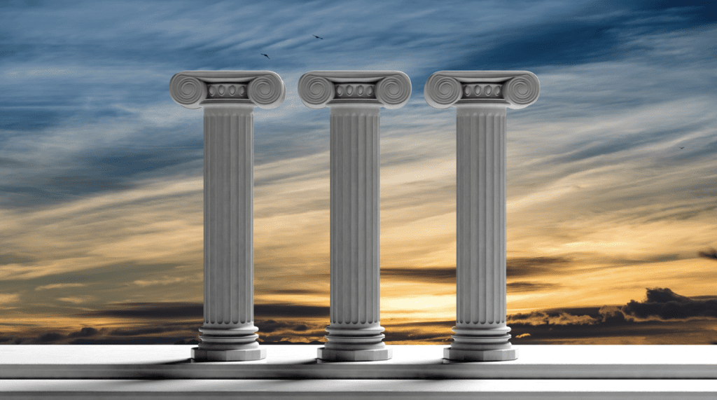 Three pillars stand in front of a sunset landscape.
