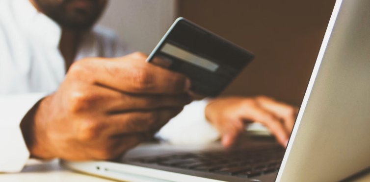 Man typing credit card number into laptop